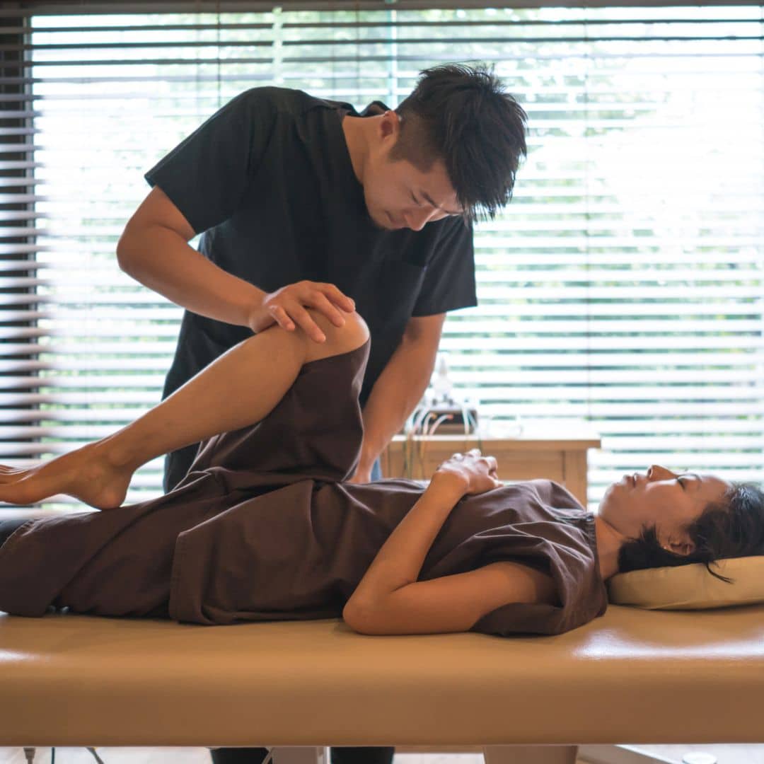 Chiropractor stretching legs and hips of patient